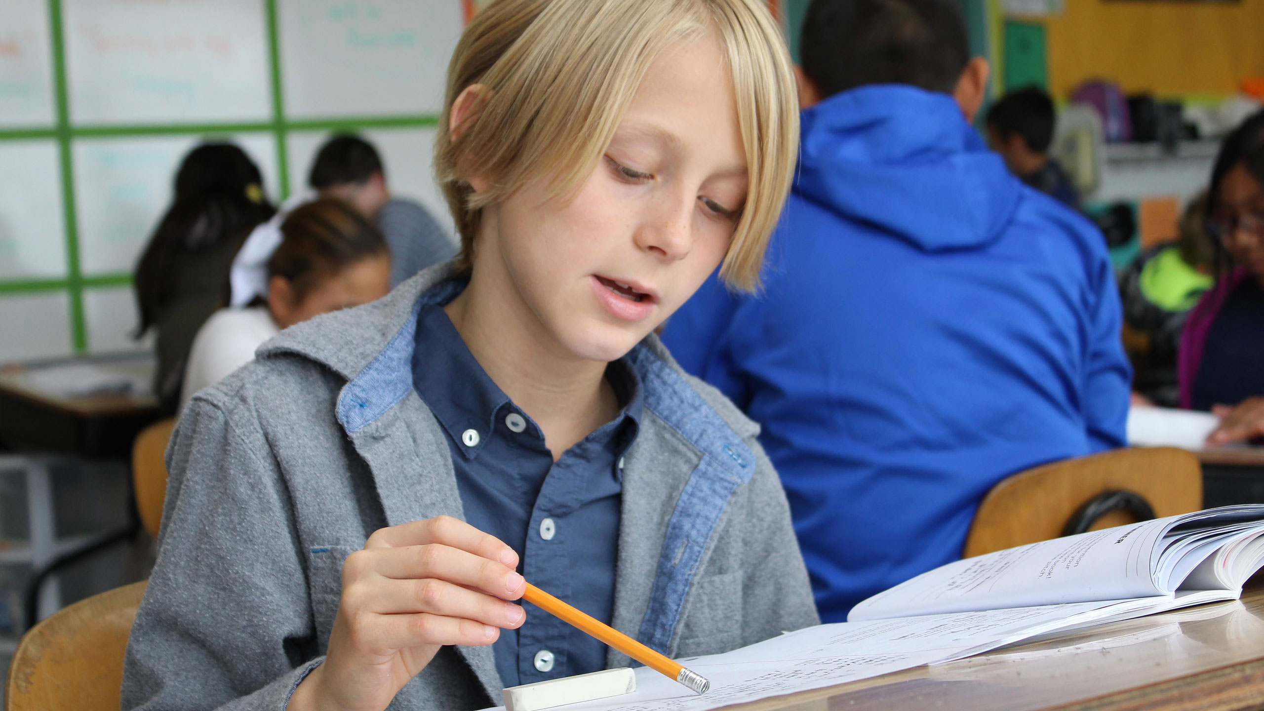 Student using a pencil to trace his place in a book